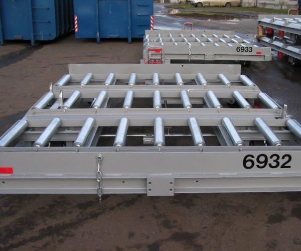 Stalowa konstrukcja rolkowa z numerem 6932 w Sławoszowicach. Szara rama, srebrne rolki, łańcuch. Element wyposażenia hali lub magazynu.