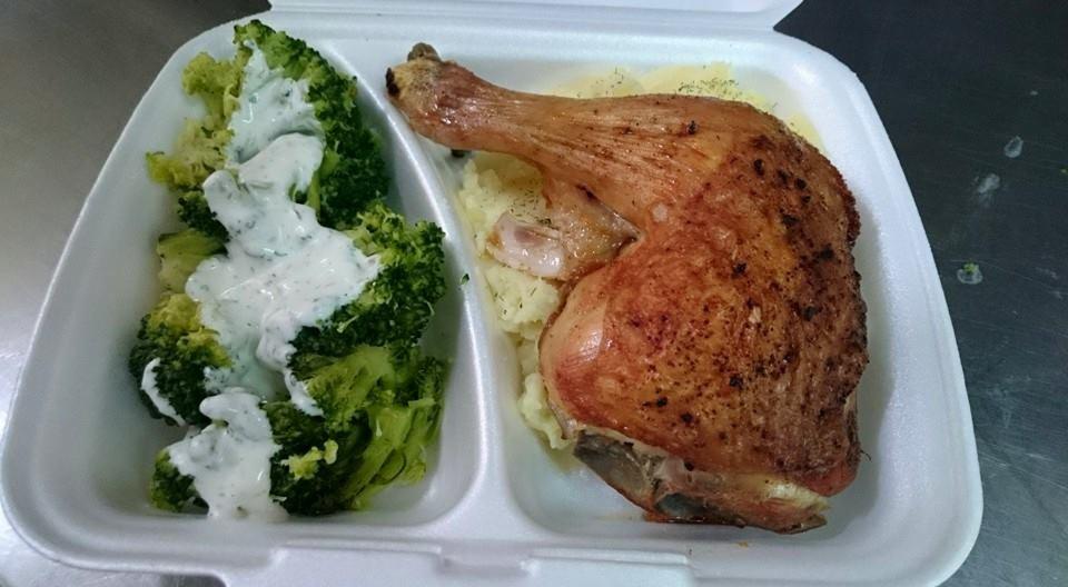 Porcja dietetyczna w białym pojemniku: pieczona noga kurczaka z ziemniakami i brokułami polanymi sosem.