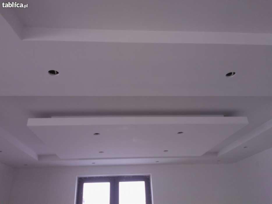 Biały, wielopoziomowy sufit podwieszany z wnękami na oświetlenie punktowe, widok na okno w dolnej części kadru.
