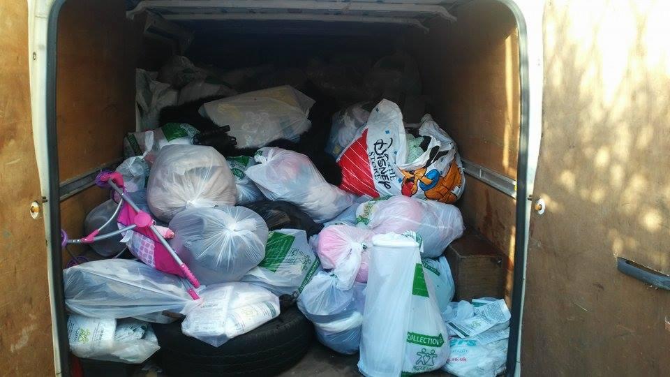 Wnętrze furgonetki wypełnionej workami z odzieżą używaną, widoczna zabawka - wózek dla lalek. Różne worki, w tym z logo Disney Store. Recykling i transport odzieży.