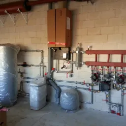 Rozbudowana instalacja grzewcza z kotłem w kartonie, zbiornikiem buforowym, zmiękczaczem wody i rozdzielaczem z pompami obiegowymi, wszystko jeszcze w folii ochronnej.