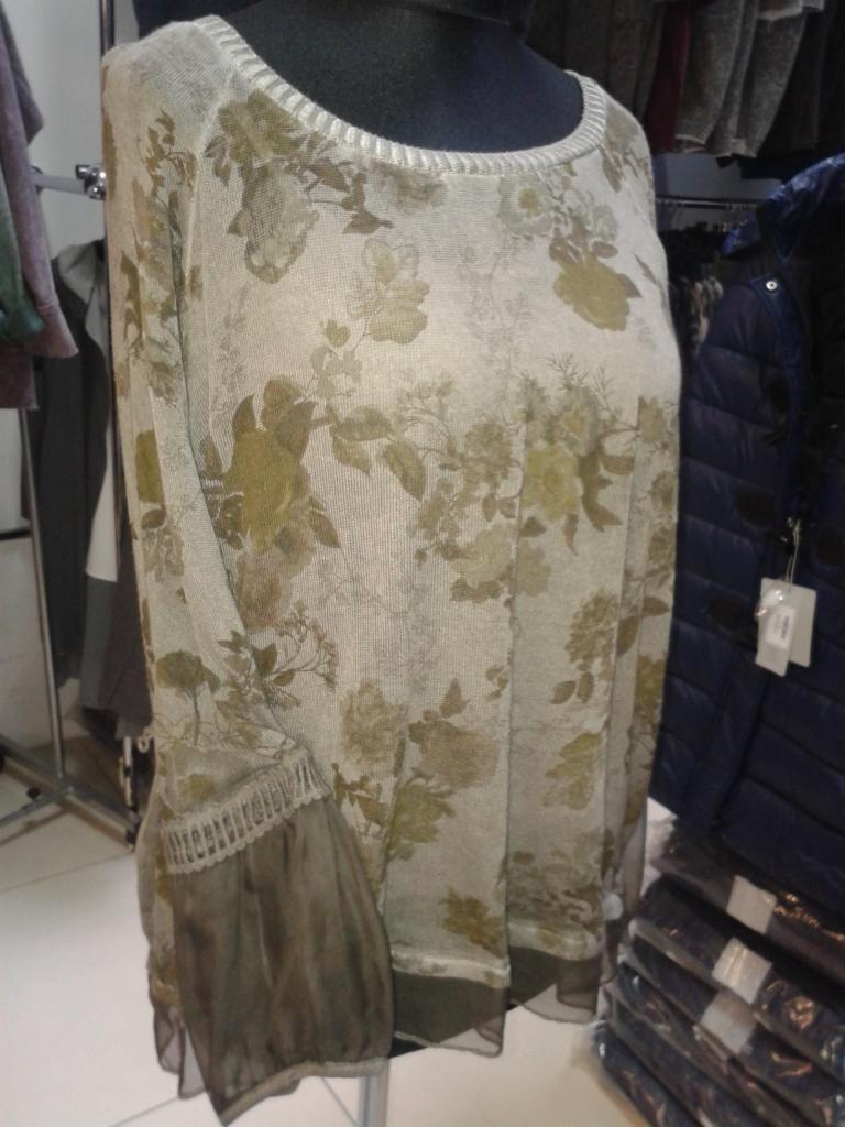 Beżowa bluzka damska z długim rękawem i kwiatowym wzorem, zaprezentowana na manekinie w sklepie odzieżowym.