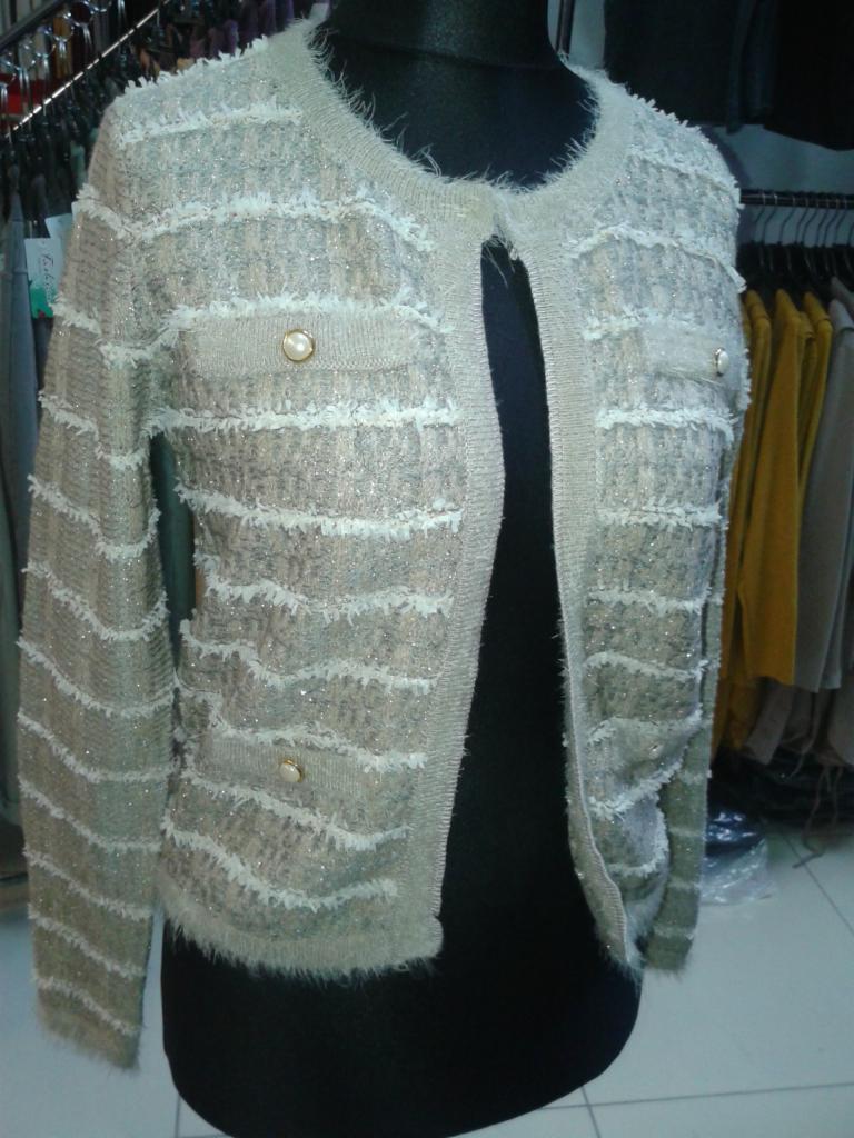 Kremowy kardigan damski z ozdobnymi paskami i perłowymi guzikami, prezentowany na manekinie w sklepie odzieżowym.