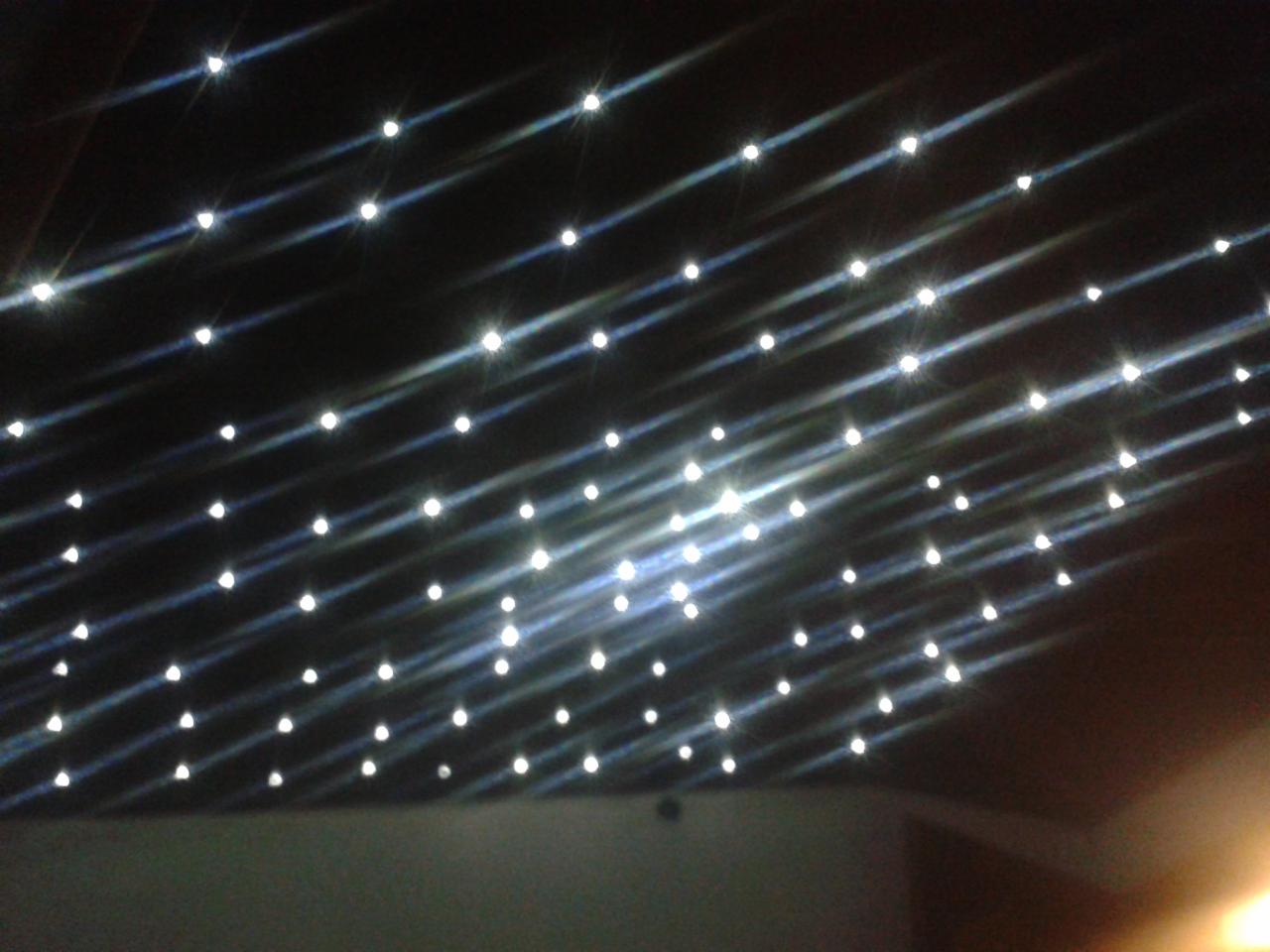 Czarny sufit napinany z równomiernie rozmieszczonymi, małymi punktami świetlnymi, tworzącymi efekt gwiaździstego nieba. Delikatne refleksy światła podkreślają głębię.