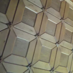 Drewniana boazeria ścienna z geometrycznym wzorem, oświetlona lampą ścienną. Wykończenie z jasnego drewna, widoczne detale łączeń i faktura materiału.