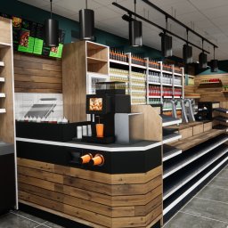 Projektownia - Wnętrze sklepu spożywczego z drewnianymi elementami, półkami z napojami i przekąskami, oraz punktem gastronomicznym z ekspozycją dań i napojów.