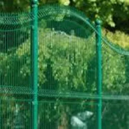 Zielone ogrodzenie panelowe z dekoracyjnym, falistym wykończeniem górnej krawędzi, na tle zieleni ogrodu. Widok z bliska, skupiony na szczegółach konstrukcji.