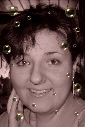 Portret kobiety z nałożonym efektem graficznym w postaci złotych kulek, uśmiechnięta twarz z kolczykami.