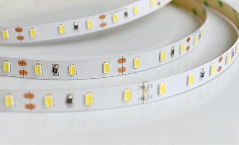 Dwie białe taśmy LED z diodami i elementami elektronicznymi, ułożone równolegle na białym tle, widoczne z bliska.