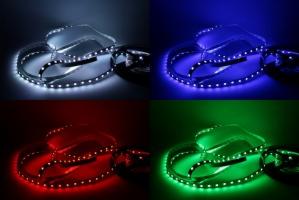 Taśma LED ułożona w kształt serca, podświetlona na biało, niebiesko, czerwono i zielono na czarnym tle, prezentująca różne barwy światła.