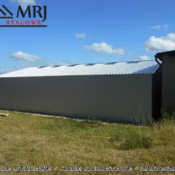 Gotowa hala z blachy trapezowej o wymiarach 10x15x3, widok z zewnątrz, szare ściany, biały dach, logo MRJ Hale Stalowe w górnym rogu.