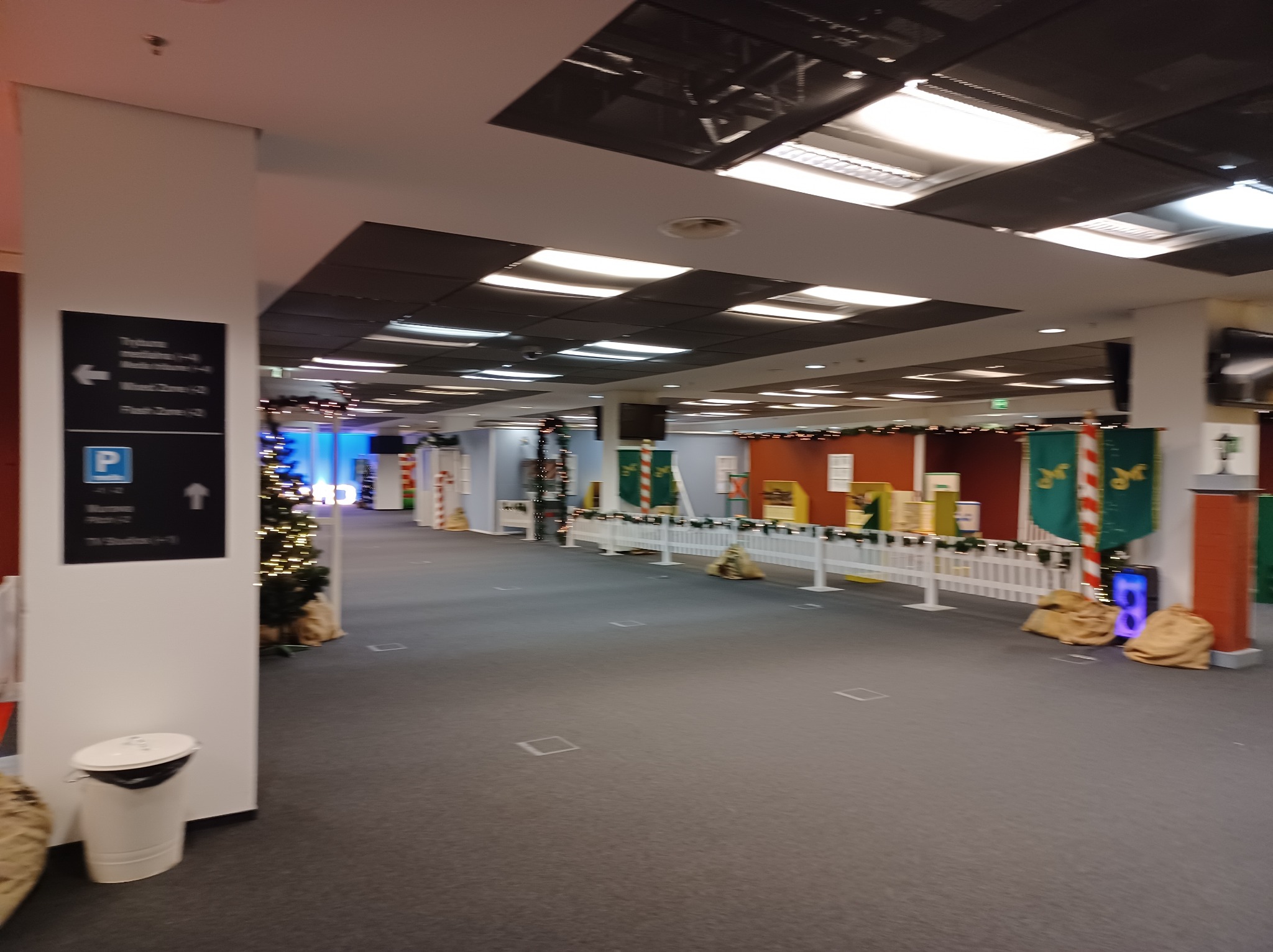 Dekoracje świąteczne w przestrzeni biurowej: choinka, płotki z girlandami, worki jutowe. W tle widoczne biura i tablica informacyjna.