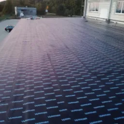 Hydroizolacja dachu płaskiego papą termozgrzewalną z logo producenta, widok z góry, Krokowa.