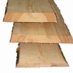 Surowe deski z widocznymi słojami drewna ułożone jedna na drugiej, ukazujące naturalną strukturę i krawędzie. Widoczne ślady po obróbce.