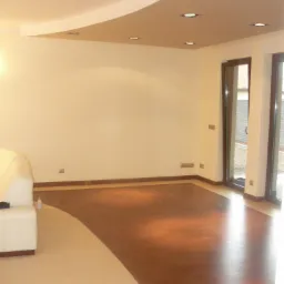 Salon z podłogą łączącą jasne płytki i ciemne panele, z oknami balkonowymi i podwieszanym sufitem z oświetleniem punktowym.