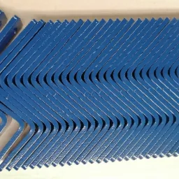 Równy rząd niebieskich, metalowych wsporników kątowych, ułożonych jeden za drugim, z widocznymi otworami montażowymi i delikatnym połyskiem farby.