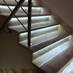 Marmurowe schody z podświetleniem LED, Bedoń-Wieś. Nowoczesne schody wewnętrzne z metalową balustradą i subtelnym oświetleniem umieszczonym pod każdym stopniem.