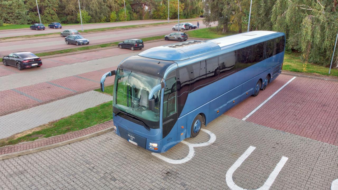 Niebieski autobus marki MAN zaparkowany na parkingu z kostki brukowej, widok z góry.
