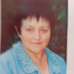 Portret kobiety w niebieskim swetrze z dekoracyjnym kołnierzem na tle zieleni, zdjęcie niskiej jakości.