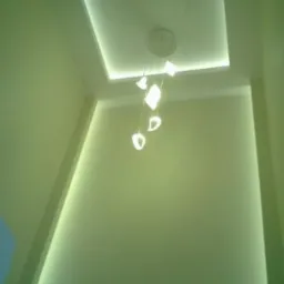 Nowoczesny sufit podwieszany z oświetleniem LED i designerską lampą wiszącą w odcieniach zieleni. Minimalistyczny design.