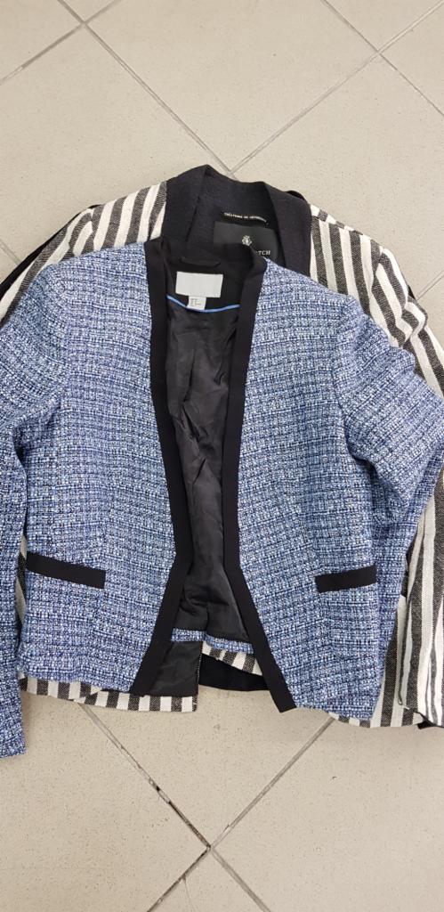 Dwa żakiety damskie: niebieski tweedowy z czarnymi lamówkami i biało-czarny w paski, leżące na jasnej podłodze.