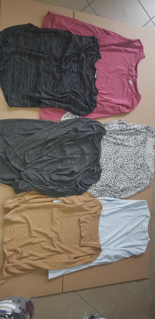 Zestaw złożonych koszulek z długim rękawem w różnych kolorach i wzorach: melanżowa szaro-czarna, różowa, szara, biała w czarne kropki, musztardowa prążkowana i błękitna.