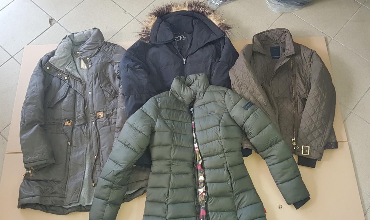 Cztery używane kurtki damskie w różnych stylach: parka z szarym futerkiem, czarna puchówka z kapturem obszytym futrem, oliwkowa kurtka pikowana i brązowa kurtka przejściowa z zamkiem błyskawicznym.