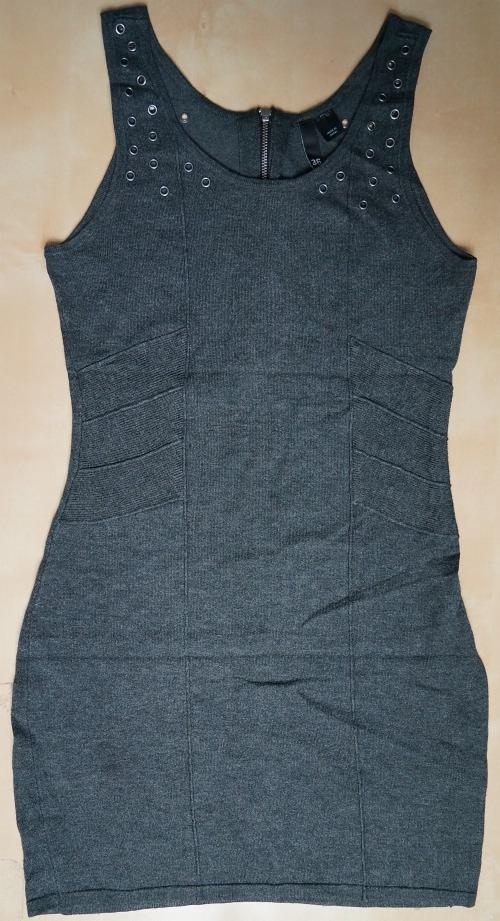 Szara, dopasowana sukienka mini bez rękawów z ozdobnymi metalowymi kółkami przy dekolcie, leżąca na jasnym tle. Widoczny zamek błyskawiczny z tyłu.