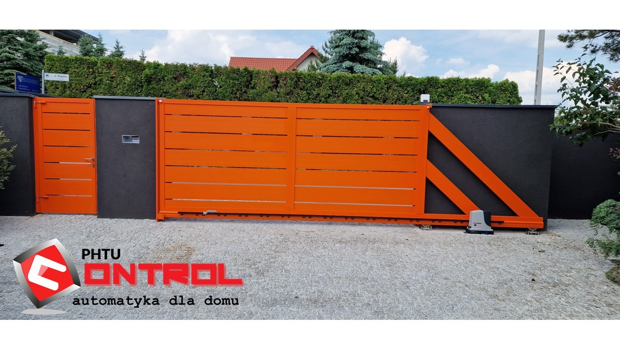 Pomarańczowa, przesuwna brama wjazdowa z automatyką, zamontowana na posesji z szarą elewacją i kostką brukową, widoczny siłownik NICE ROBUS HIGH SPEED.
