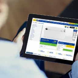 Ekran laptopa prezentuje stronę internetową firmy Arabian Designer z grafiką architektoniczną w odcieniach czerwieni i niebieskiego oraz hasłem ARCHITECTURE & INTERIOR DESIGN.