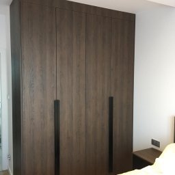 AS line - Duża, czterodrzwiowa szafa wnękowa z ciemnego drewna z pionowymi, czarnymi uchwytami, idealnie dopasowana do wnętrza sypialni w Tychach.