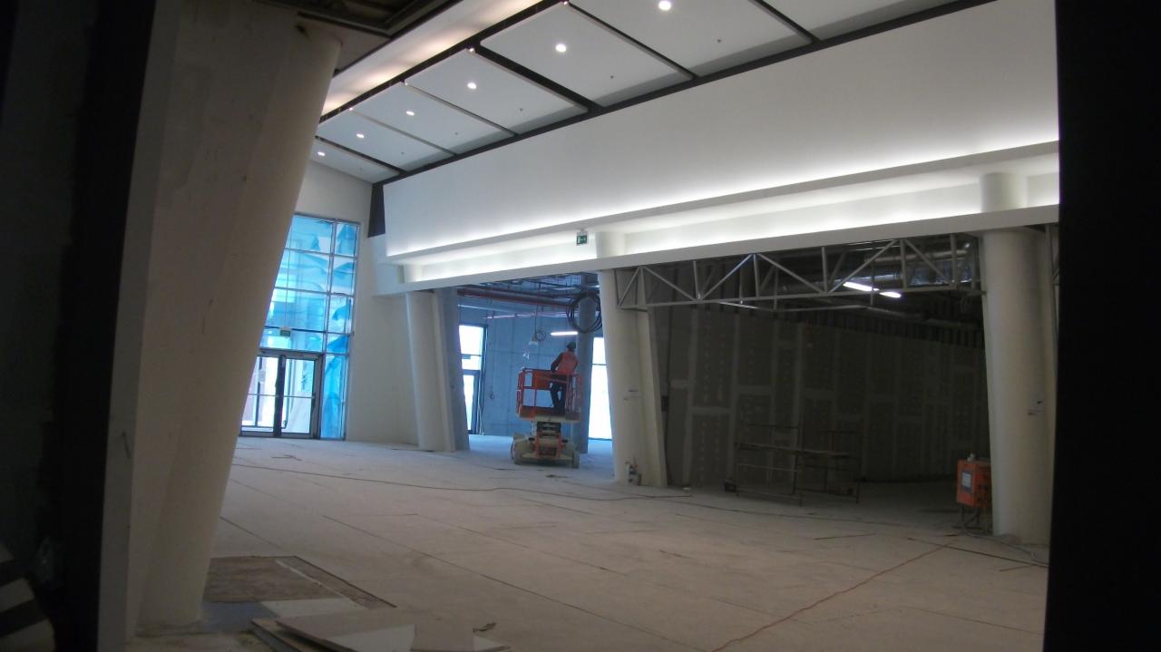 Przestronne wnętrze w trakcie wyburzania ścian w Będzinie. Widoczny pracownik na podnośniku i przygotowane ściany do usunięcia. Duża przestrzeń z kolumnami.