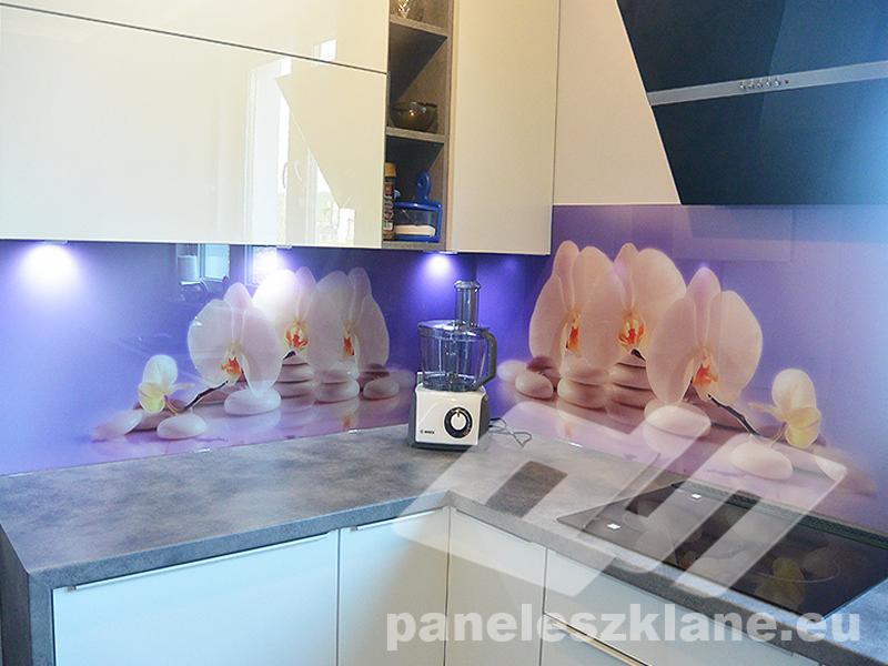 Szklany panel kuchenny z motywem białych orchidei i kamieni zen, podświetlony punktowo, z widocznym robotem kuchennym na blacie.