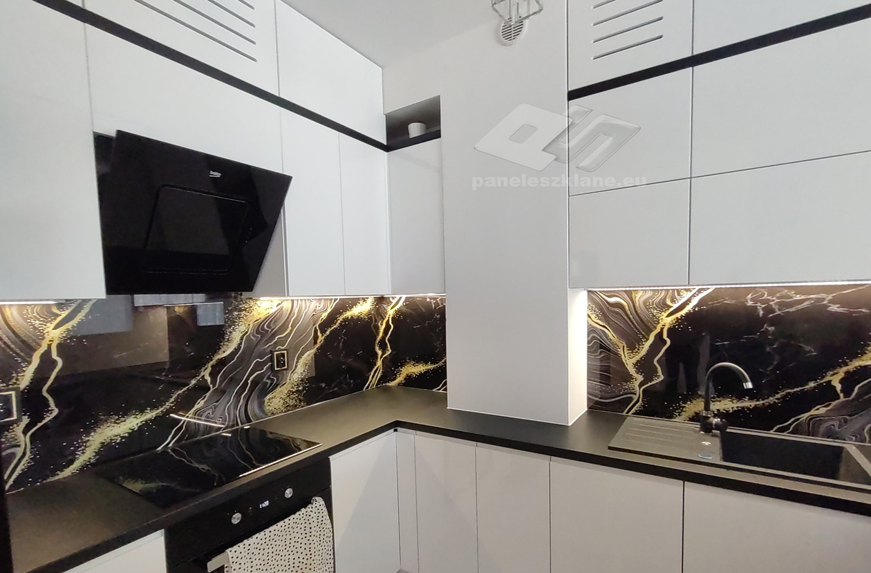 Nowoczesna kuchnia z białymi szafkami i czarnym blatem, ozdobiona szklanym panelem ściennym z motywem czarnego marmuru ze złotymi żyłami, oświetlonym od góry.