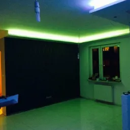 Nowoczesne oświetlenie LED w salonie z czarną ścianą dekoracyjną i podwieszanym sufitem. Realizacja w Rawa Mazowiecka. Energooszczędne rozwiązania.