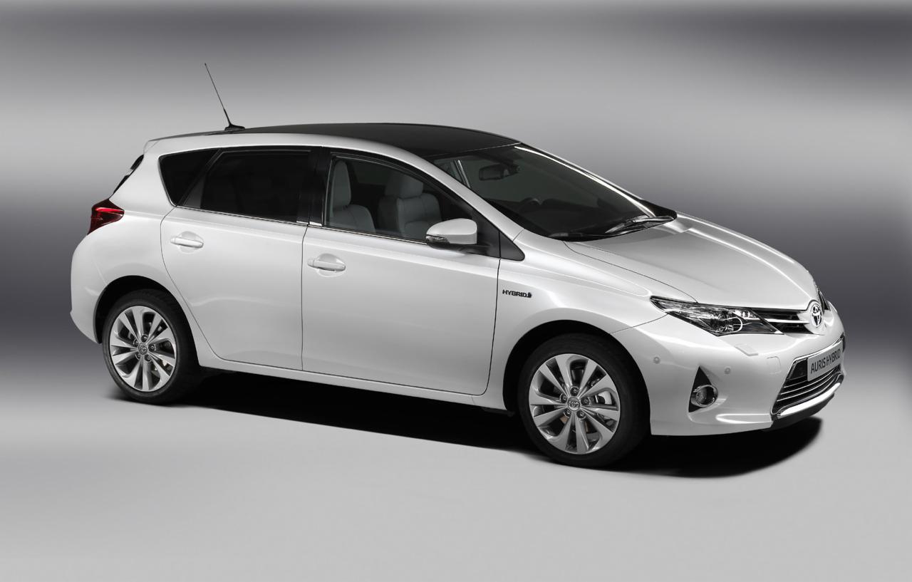 Biała Toyota Auris Hybrid z czarnym dachem, prezentowana w studio na jednolitym szarym tle, z widocznym logo 'Hybrid' na przednim błotniku.