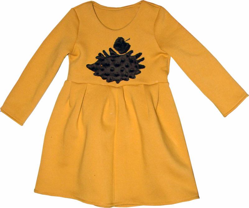 Żółta sukienka dziecięca z długim rękawem, ozdobiona aplikacją jeża z jabłkiem na brzuchu, widoczna na białym tle.