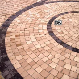 Kreatywny wzór z kostki brukowej w odcieniach beżu i brązu, ułożony w okrągły kształt z numerem '02' w centrum.