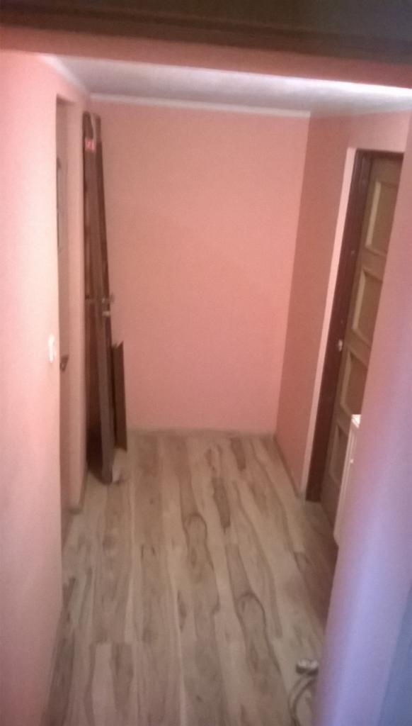 Wnętrze po remoncie w Ludwikowicach Kłodzkich: świeżo pomalowane ściany w odcieniach różu, panele podłogowe imitujące drewno, nowe drzwi.