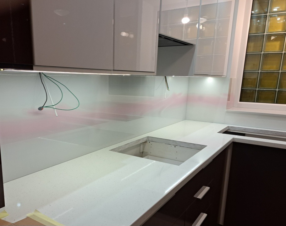Szklany panel ścienny w kuchni, montowany nad blatem w Mińsku Mazowieckim, z widocznymi przewodami elektrycznymi do oświetlenia podszafkowego.