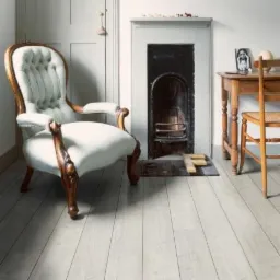 Jasna podłoga z paneli drewnianych w salonie z kominkiem i stylowym fotelem. Minimalistyczne wnętrze z akcentami vintage i oświetleniem dziennym.