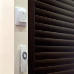 Ciemnobrązowe, plisowane rolety okienne z panelem sterowania i pilotem na ścianie. Nowoczesne rozwiązanie regulacji światła w pomieszczeniu.