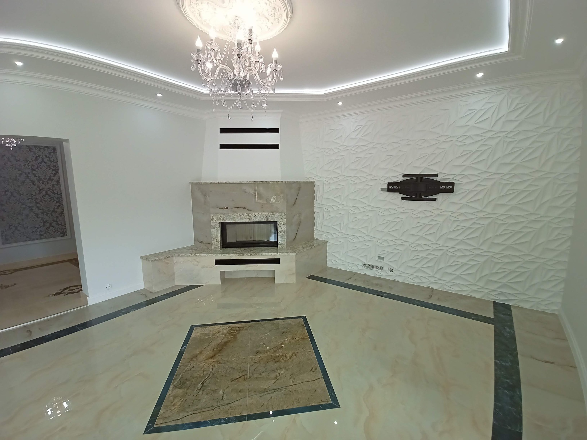 Eleganckie wnętrze salonu z marmurową podłogą, kominkiem obłożonym marmurem, kryształowym żyrandolem i ścianą z trójwymiarową teksturą.