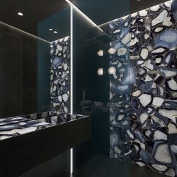 Kilandesign - Nowoczesna łazienka z czarnymi płytkami i umywalką z kamienia agatowego, oświetlona listwami LED, z deszczownicą i dekoracyjnymi lampami kulami.