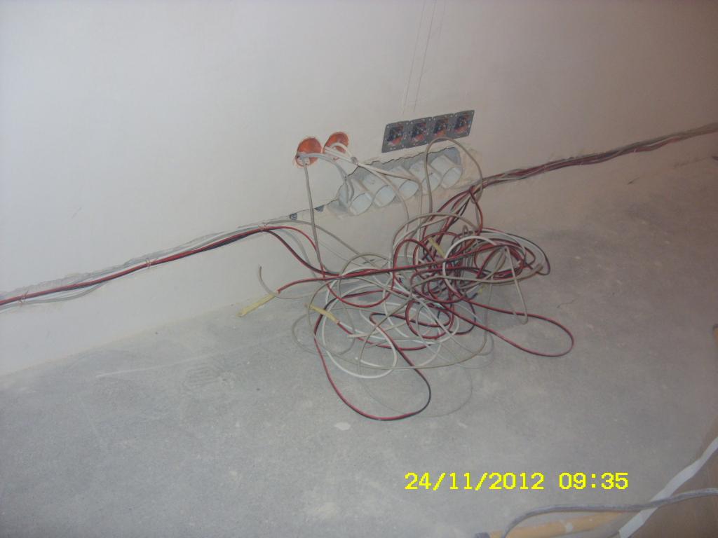 Wiązka przewodów elektrycznych w peszlach, wystających ze ściany w surowym wnętrzu, widoczne puszki instalacyjne i listwy montażowe, data na zdjęciu: 24/11/2012.