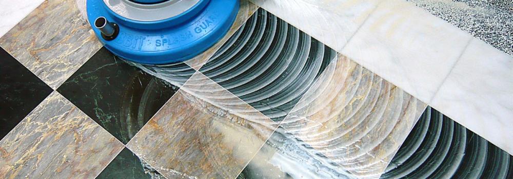 Polerowanie marmurowej podłogi z wzorem szachownicy za pomocą polerki z niebieską osłoną. Widoczne ślady po polerowaniu na powierzchni.