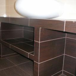 LUKSUS Styl  ŁUKASZ KORNILAK - Łazienka: zabudowa pod umywalkę z ciemnobrązowych płytek z jasną fugą, widoczna umywalka i fragment wanny z mozaiką. Ujęcie z dołu, podkreślające geometryczny wzór.