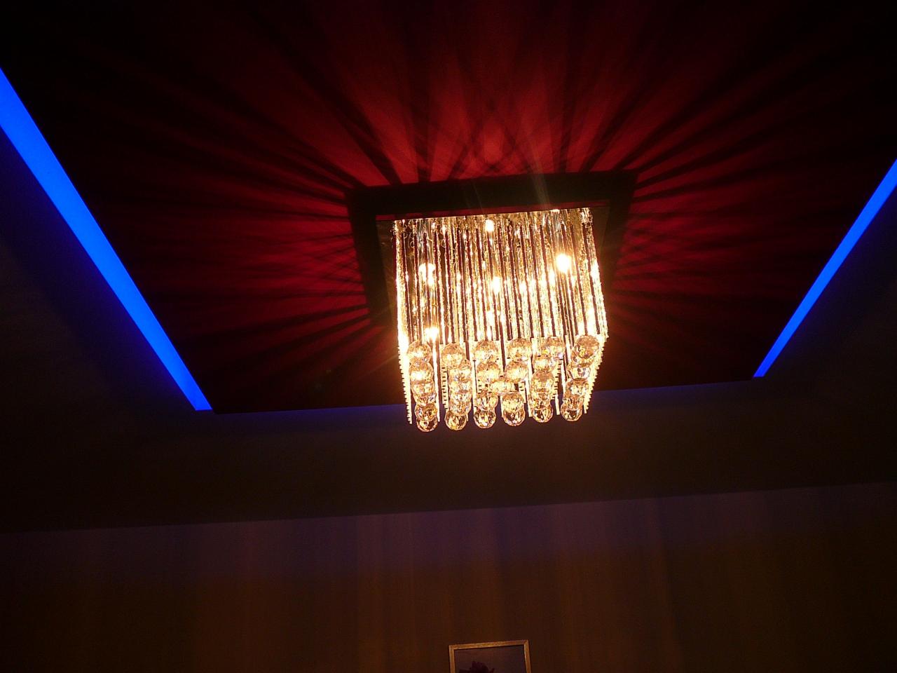 Kryształowy żyrandol z efektem świetlnym na suficie podwieszanym z niebieskim oświetleniem LED. Czerwone refleksy na suficie.