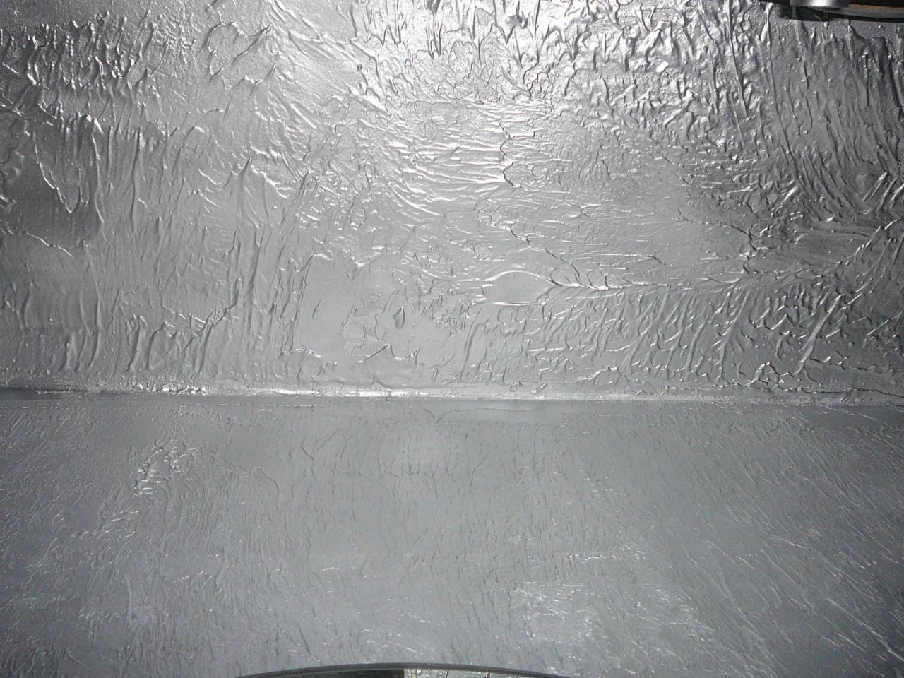 Srebrna ściana z wyraźną fakturą, przypominająca gipsowe wykończenie z efektem 'skóry słonia', z delikatnym połyskiem i widocznym podziałem na dwie płaszczyzny.