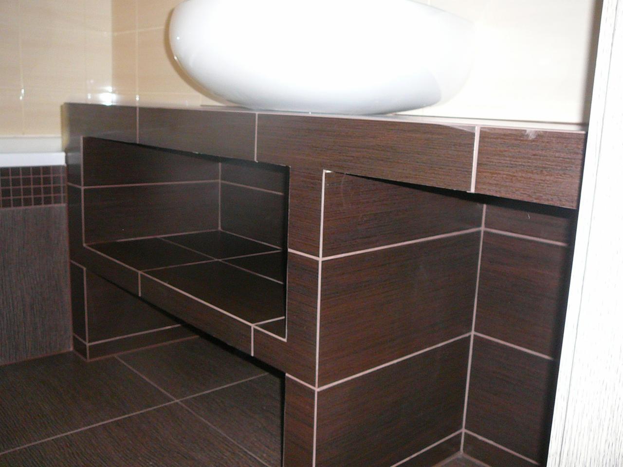 Łazienka: zabudowa pod umywalkę z ciemnobrązowych płytek z jasną fugą, widoczna umywalka i fragment wanny z mozaiką. Ujęcie z dołu, podkreślające geometryczny wzór.